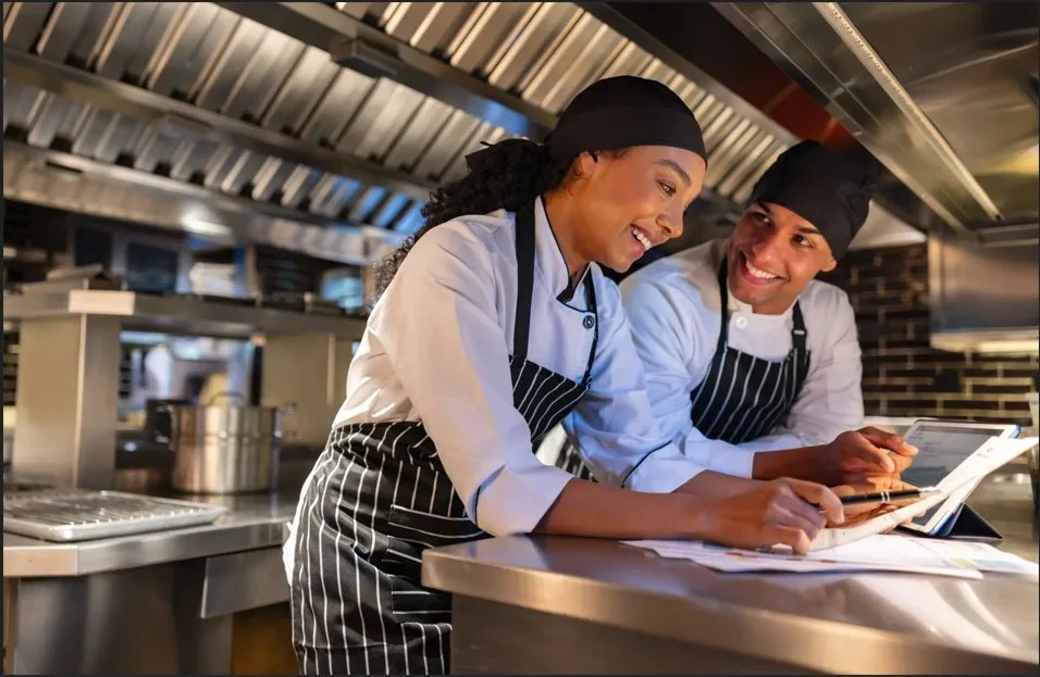 Chefs using GNV compliance platform on tablet in institutional kitchen